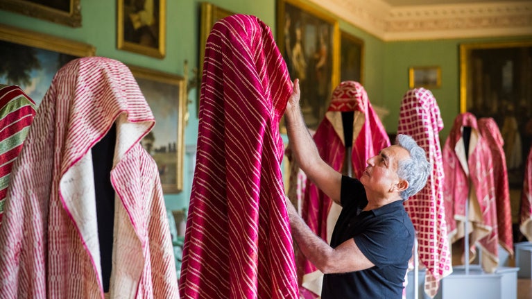 Karun Thakar dresses a mannequin in red clothes against the backdrop of Osterley's interiors
